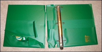 The inside of a well-used heavy duty reference 3 ring binder, showing the front cover almost completely ripped off and the two front pockets badly torn.