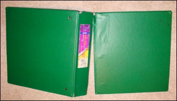 The very well used heavy duty notebook, opened up to show the front cover almost torn off.