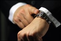 Business man pointing to the watch on his wrist.