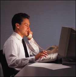 Business man on phone in front of a computer.