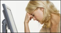 Woman leaning on her hand in front of a computer monitor, concerned.