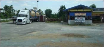 A truck parked in a run down parking lot, as if abandoned.