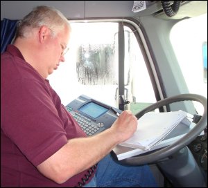 Mike writes down information from the QualComm MCT into his load assignment notebook, using the aluminum forms holder as a solid, desk-like surface.