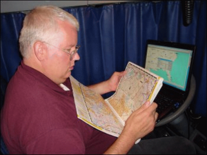 Mike Simons looks at his motor carriers atlas with his laptop computer running Auto Map in the background.