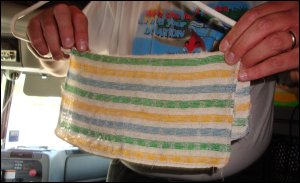 Hanging up a damp dishcloth to dry on a plastic hanger hanging from the top bunk.