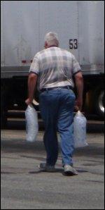 Mike totes two bags of ice back to his truck to put in his ice chest.