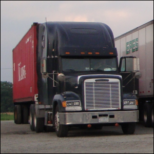 A big truck in a truck stop parking lot.