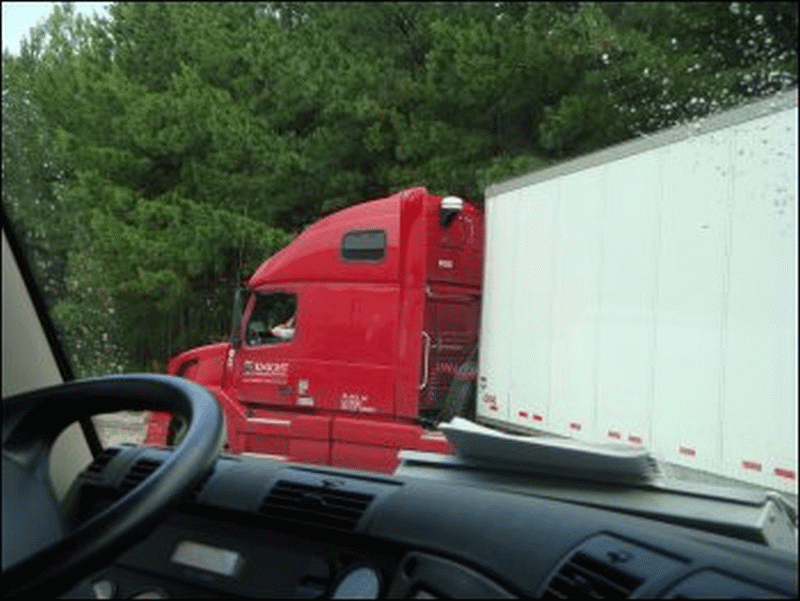 A professional truck driver is backing his rig into a dock on our right hand side.