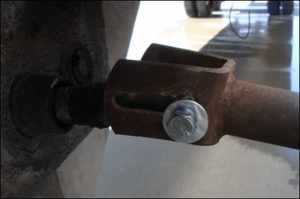 A new bolt, about 3 inches long, has been inserted through a washer and then through the holes to connect the landing gear shaft with the crank handle, and then fastened in place with another washer and then a nut. 