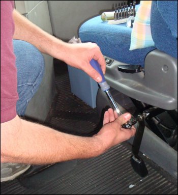 Mike removed the seat belt buckle screw on the left side of the passenger seat first, using a ratchet and T50 Torx bit.