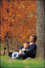 A mother and son under a tree in the fall, as if during Thanksgiving.