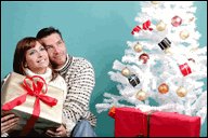 Couple celebrating Christmas with a gift and Christmas tree.