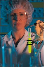 A technician in a chemical laboratory using a dropper to drip a liquid into a test tube.