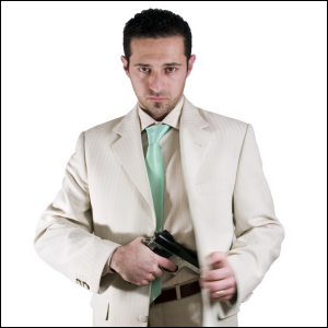 Man in suit and tie with a gun.