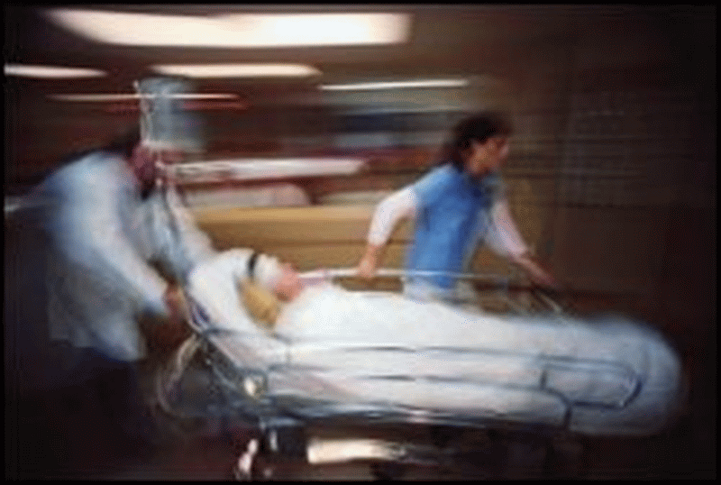 A patient is rushed down the hallway of a medical facility by health care professionals.