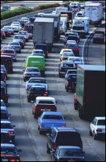 Heavy traffic on the road including big trucks and cars.