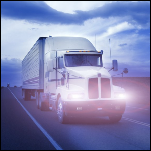 A truck running with its lights on at twilight.