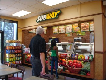 Professional driver Mike Simons waits his turn to order a meal for him and Vicki at a Subway fast food restaurant at a truck stop with rewards program points.