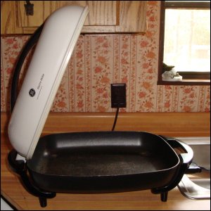 electric skillet with lid propped on handle for condensation to run back down into base
