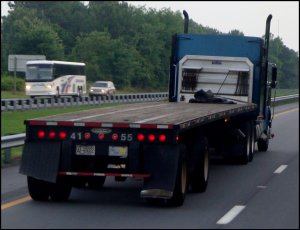 Flatbed truck with rear lights on in dusk conditions.