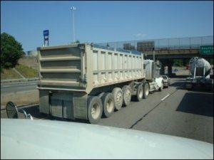 A big truck tailgating a car at highway speeds on I-20 so close that it looks like the truck is pushing the car down the road.