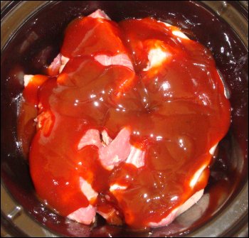 The third and final layer of pork ribs with barbeque sauce covering them in a crock pot.