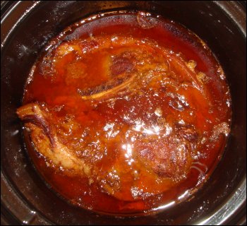 Country-style pork ribs with barbeque sauce after cooking in a crock pot.