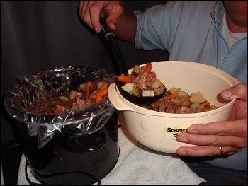 Mike scoops the vegetables from the top of the crock pot before serving up the meat from this batch of beef stew.