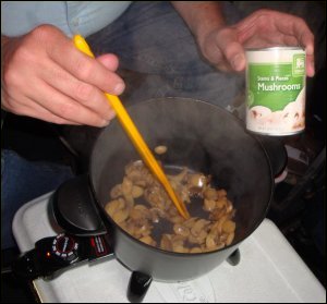 Heating and sauteing drained canned mushrooms in a hot pot.
