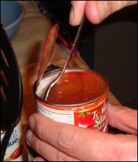 Stirring the water in the tomato sauce can to get out as much sauce as possible.