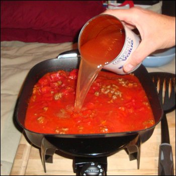 Using the diced tomato can as a measuring cup to pour water into the skillet to cook the beefaroni.