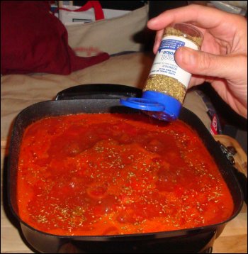 Adding spices to the homemade beefaroni dish.