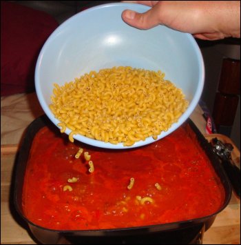 Pouring the macaroni into the tomato sauce mixture to make beefaroni.