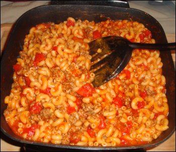 A close-up view of the beefaroni as it has been prepared in one skillet, showing the meat and diced tomatoes.