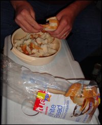 Mike Simons prepares his famous bread dressing by tearing into pieces a loaf of cheap white bread.