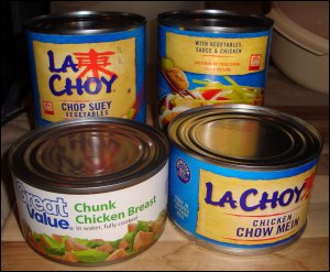 The vegetable and sauce cans from a La Choy chicken chow mein dinner, shown with an extra can of chop suey vegetables and a can of chunk chicken breast.