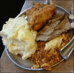 A sizeable quantity of mashed potatoes served from a truck stop restaurant buffet is shown with other food items.