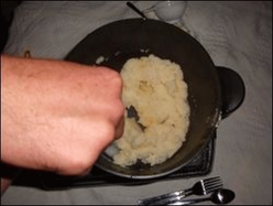 Mike stirs the potato flakes into the water and milk mixture in the hot pot. When they are nice and thick, then they are ready to eat.