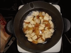 Diced veggies are shown in water in a hot pot, being ready for boiling.