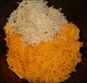 Top the elbow macaroni and Velveeta with shredded cheddar cheese and mozzarella cheese in the crock pot for macaroni and cheese.