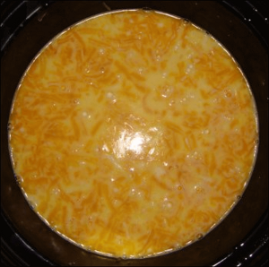 Part way through the cooking period, crock pot macaroni and cheese shows that some of the cheese has come to the top of the milk mixture.