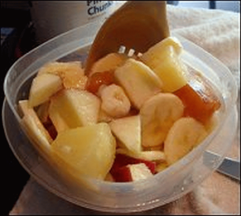 Mike mixed up the fruit in the fruit salad to make sure every was coated with the syrup, especially the banana and apple.