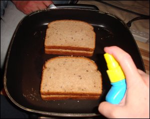 Once the butter-side-down slice is in the electric skillet, Vicki sprays the top slice of bread to make sure that both sides of the grilled cheese sandwich have the opportunity to become golden brown.