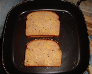 Both of the grilled cheese sandwiches have been buttered on both sides and are being pan grilled.