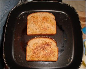 The pair of grilled cheese sandwiches are browning nicely in the electric skillet.