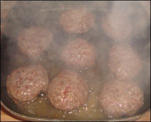 Hamburgers being cooked in an electric skillet.
