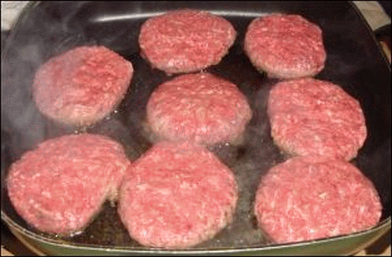 Eight hamburgers being cooked in an electric skillet.