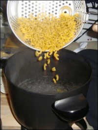 Putting the dry elbow macaroni into boiling water in a hot pot for macaroni and cheese.