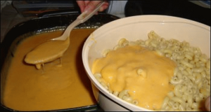 Spooning cheese sauce over the cooked macaroni for macaroni and cheese.
