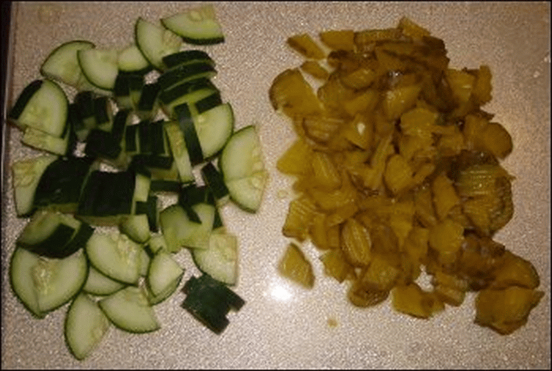 Cut up portions of cucumber and pickle for mean pea salad.